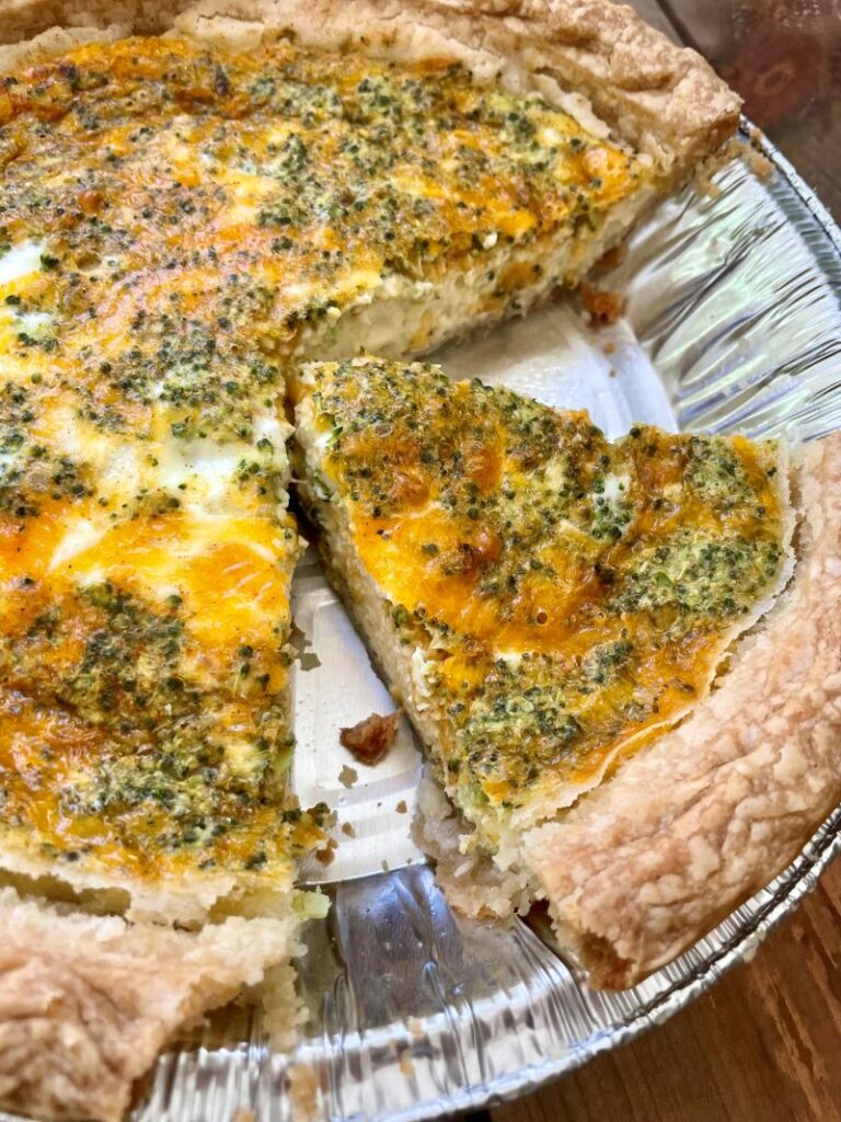broccoli cheddar quiche with slice cut in pie tin