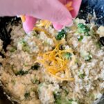 adding the cheese topping evenly over the top of the crockpot casserole